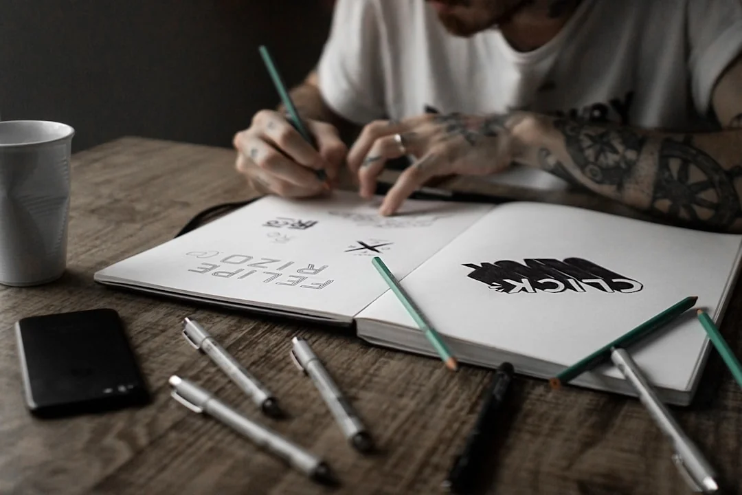 Tattooed hand holding a red book about design.